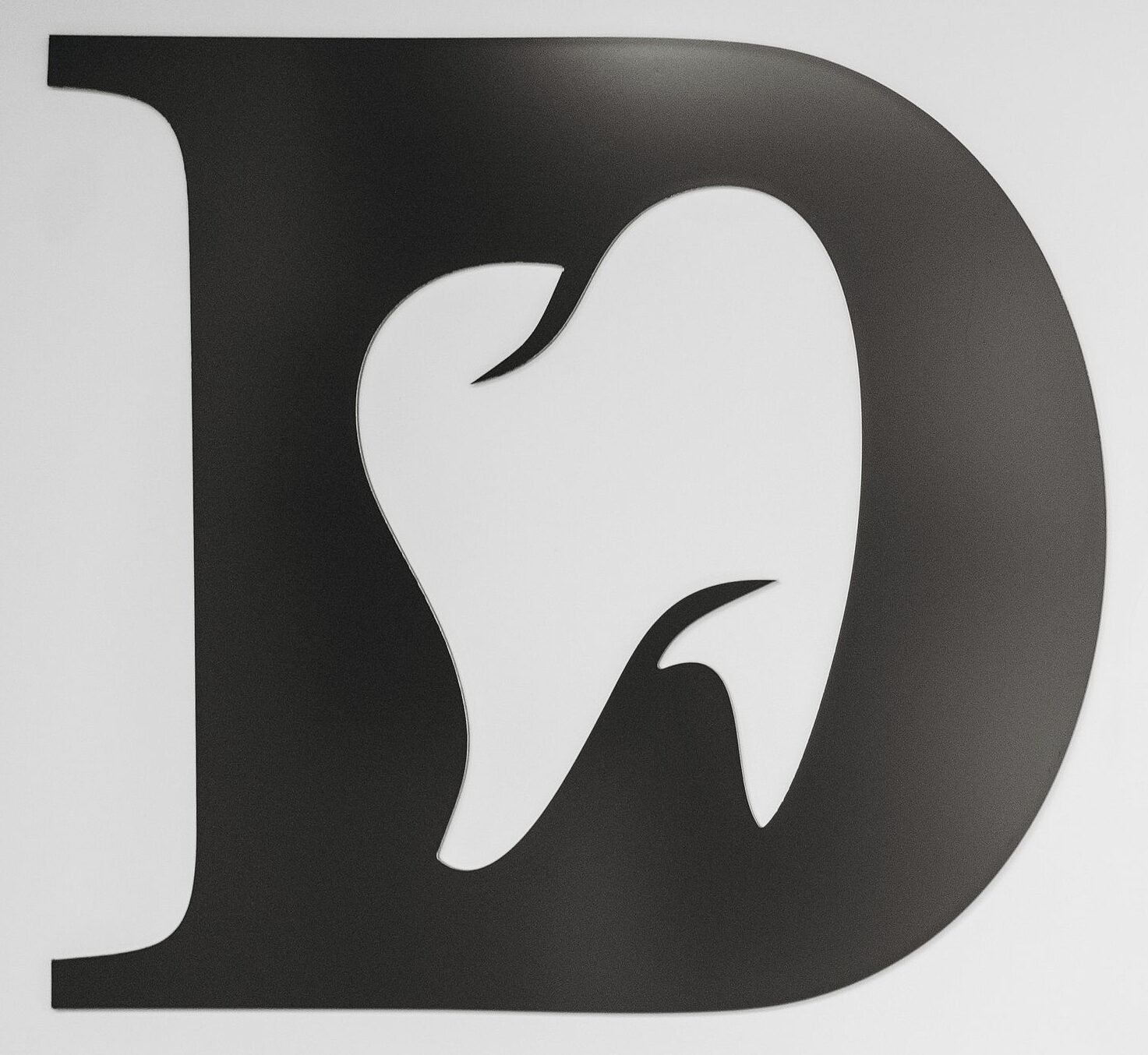 Simple black and white tooth design within letter D, ideal for dental branding.